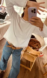 Remera negra de algodón con cuello redondo y bordados blancos en cuello, puños y ruedo. Corte recto.