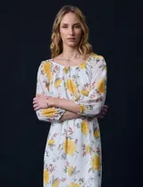 Vestido corto de gasa estampada con flores amarillas, marca Sandra Darren. Tiene escote redondo, mangas 3/4 con puño elastizado y lazo de ajuste en la cintura.