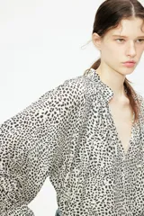 Blusa oversized con cuello elevado fruncido, abertura en V adelante y bajo recto. Mangas globo largas de corte raglán con abertura y botón en los puños.