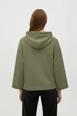 Buzo con capucha color crudo o natural, de manga larga y calce holgado. Presenta un diseño sutil bordado en el frente.