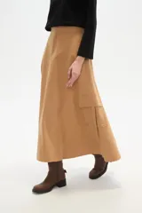 Falda larga color camel, corte evasé, confeccionada en algodón, con un bolsillo cargo grande en el lateral derecho.