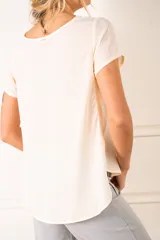 Blusa color crudo de poliéster con mangas cortas y cuello redondo.