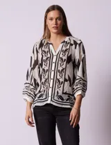 Blusa de gasa estampada marca Figueroa & Flower, color blanco con estampado abstracto en negro. Tiene cuello a la base con escote en V, apertura central con botones y mangas largas ¾ amplias.
