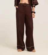 Pantalón wide leg de cintura alta color marrón, confeccionado en viscolino con 15% de lino, con trabillas en la cintura y vieses contrastantes en las barras. Incluye cinturón de tejido con hebilla metalizada de efecto martillado.