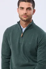 Buzo tejido de algodón color verde oscuro, con cuello alto y cierre frontal parcial con detalle de cuero en el tirador. Presenta un logo bordado en el pecho.