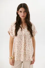 Blusa estampada con hojas color beige, escote en V y mangas cortas.