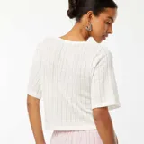 Camiseta cropped de punto calado color beige, con escote en V y cierre frontal con lazos.
