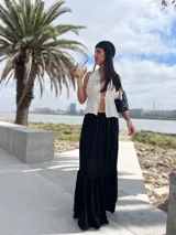 Falda larga negra de corte amplio con volados en el ruedo.