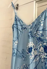 Vestido midi celeste con estampado floral en tonos azules y blancos, de breteles finos y corte al cuerpo.