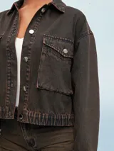 Campera de jean celeste con efecto lavado, corte cropped, cuello clásico, cierre frontal con botones metálicos, cuatro bolsillos frontales con solapa y puños abotonados.