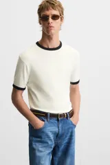Camiseta azul marino de corte recto, con cuello redondo y mangas cortas. Presenta ribete blanco en cuello y mangas.