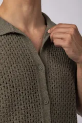 Camisa negra tejida de manga corta, con calado aireado, cuello tipo bowling y botones al tono. Diseño de corte relajado.