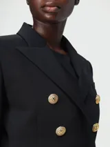 Blazer negro entallado de Balmain con doble botonadura y seis botones dorados.