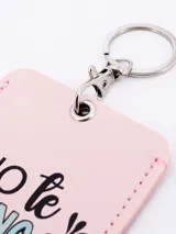 Llavero porta tarjeta rosado con frase motivacional estampada en letras de colores.