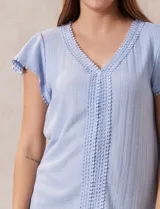 Blusa blanca de tejido pointelle con escote en V y aplique de puntilla en el cuello y mangas cortas con volados.