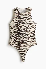 Body colaless de punto elástico suave con estampado de cebra en tonos blanco y negro. Tiene escote redondo y botones a presión ocultos en la entrepierna.