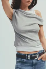 Camiseta blanca con musculosa gris superpuesta con escote asimétrico.