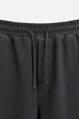 Bermuda negra de corte relaxed fit, con cintura elástica ajustable con cordón, bolsillos frontales y bolsillo trasero de parche.