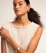 Blusa de punto color beige, sin mangas, con escote redondo y bajo asimétrico.