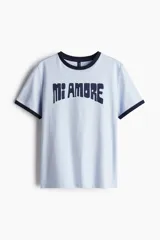 Remera celeste con cuello y mangas con ribete azul marino. Estampa frontal con la frase "Mi Amore" en azul marino.