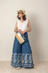 Pantalón italiano de jean azul con bordados florales en color crema. Tiene cintura elastizada con cordón ajustable y bolsillos laterales.