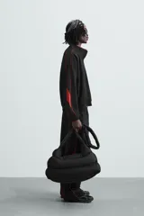 Chaqueta deportiva negra con cuello alto, cierre frontal con cremallera y ribetes rojos en hombros y mangas.