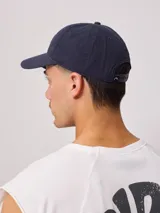 Gorra de lona lavada color beige con visera verde y parche con el logo de Rusty en el frente.