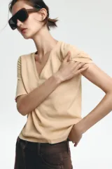 Camiseta color beige de lino con cuello en V y mangas cortas.