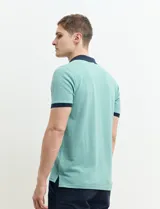 Remera polo blanca de piqué con cuello y puños en azul marino. Tiene tapeta de dos botones y bolsillo de parche en el pecho.