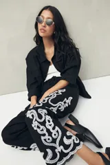 Pantalón recto negro de algodón con bordado artesanal blanco a contratono en los laterales y ruedo.