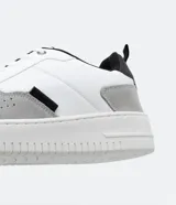 Championes urbanos de cuero sintético blanco con recortes en gris y negro, cierre con cordones y suela de goma.