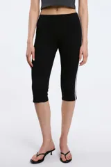 Calzas capri negras con cintura elástica y una raya blanca vertical a lo largo de la pierna.