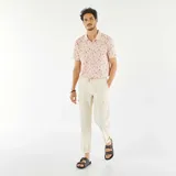 Remera polo de piqué de algodón color rosa con estampado de palmeras y tablas de surf en negro.