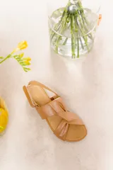 Sandalias bajas doradas con tiras de cuero entrelazadas y ajuste con hebilla al tobillo.