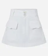 Short pollera de sarga color blanco, con trabillas en la cintura, cierre tradicional, botones dobles y bolsillos cargo delanteros.
