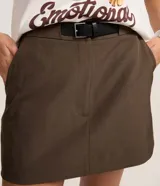 Short pollera de sastrería color marrón, de corte recto y estilo alfatado, con cierre tradicional y bolsillos. Incluye cinturón desmontable de poliuretano.