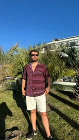 Camisa de manga corta con cuello clásico y estampado con motivos geométricos en tonos borgoña, azul y blanco.