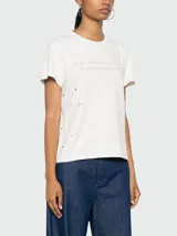 Remera de algodón color blanco con estampa de texto en el frente y manchas negras.
