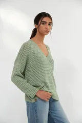 Sweater verde claro de tejido de punto calado con escote en V y mangas largas.