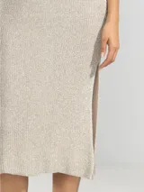 Vestido largo tejido en jersey con hilo lurex dorado, de corte recto, escote bote y aberturas laterales.