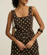 Vestido midi evasé de tricolina color marrón con lunares blancos, breteles anchos y escote cuadrado. Presenta lastex en la espalda y recorte fruncido en la cintura.