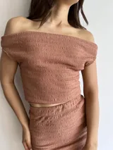 Conjunto color beige de tela bambula elastizada, compuesto por un top off-shoulder y una falda midi ajustada.