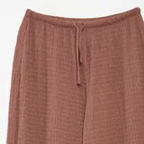 Pantalón ancho color ladrillo, de punto crepé con textura tipo waffle y cintura con cordón ajustable.