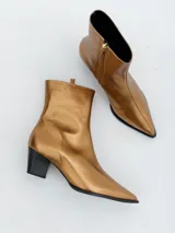 Botín de cuero con estampado animal print de cebra en tonos beige y negro, con punta fina y taco geométrico.