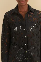 Camisa negra de encaje con cuello clásico, cierre frontal con botones y mangas largas.
