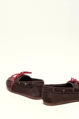 Mocasín tipo boat shoe con estampado de vaca en tonos marrón y blanco, confeccionado en cuero. Cuenta con cordones de cuero marrón oscuro y suela de goma.