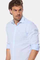 Camisa de manga larga, color celeste con finas rayas blancas, confeccionada en una mezcla de lino y algodón. Presenta un corte slim fit y no tiene bolsillo.