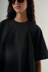 Camiseta negra de algodón con corte amplio y mangas cortas. Presenta un pequeño bordado sutil en el pecho.