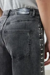 Pantalón de jean gris oscuro, corte wide leg, con tachas plateadas en los laterales.