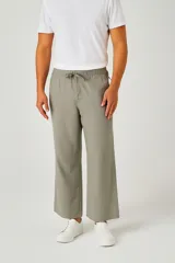 Pantalón de lino color verde oliva, tiro bajo, corte slim fit y largo. Presenta cordón ajustable en la cintura y bolsillos laterales.